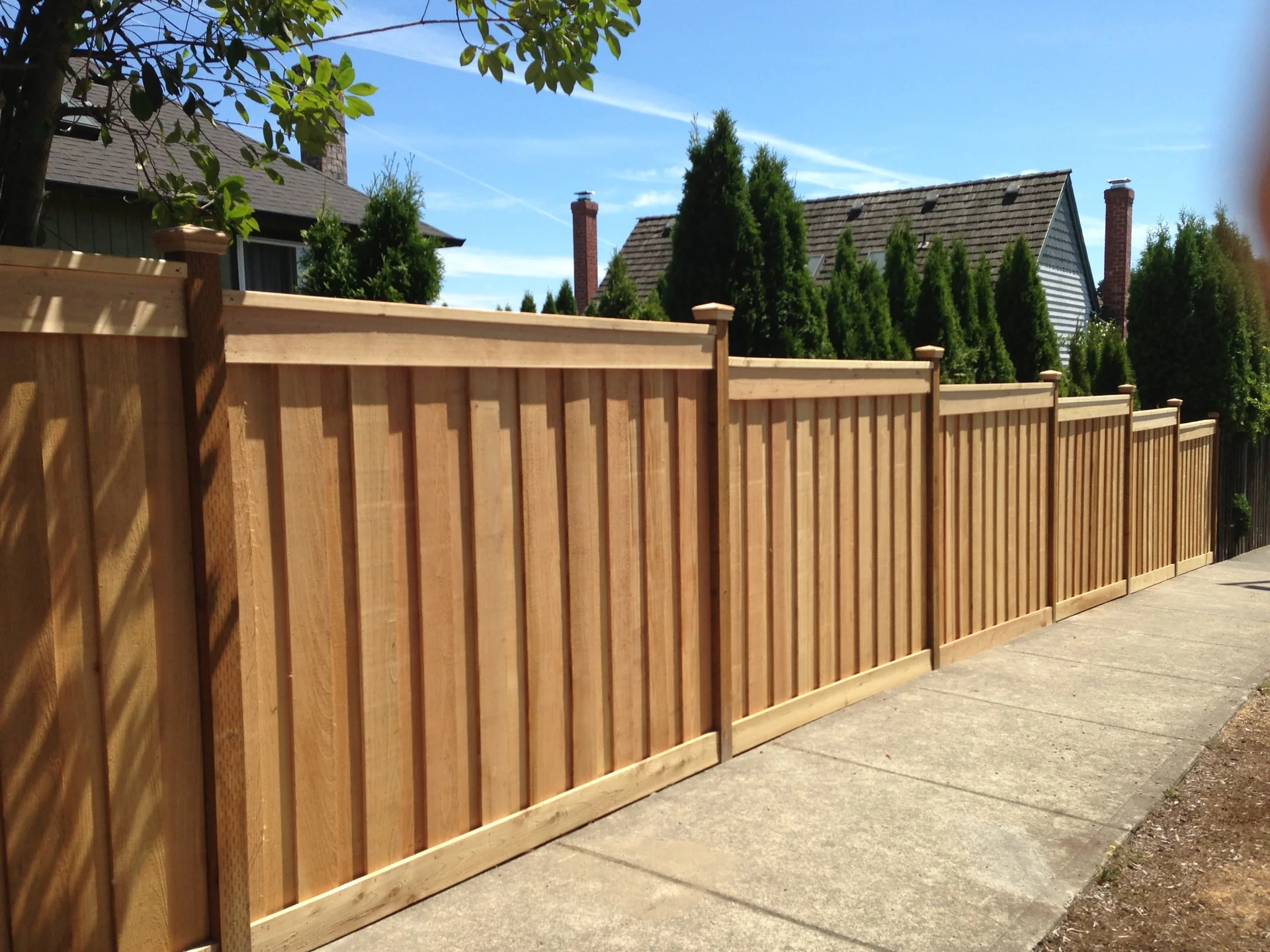 Finished picture-frame cedar privacy fence beside a landscaped walkway
